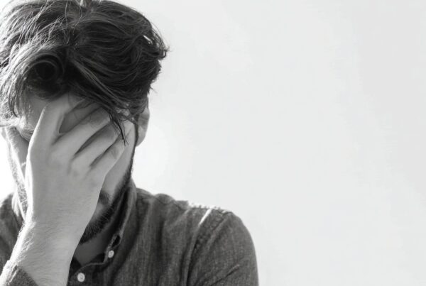 A distressed man covers his face in discomfort, illustrating the emotional toll tied to what are high eyes.