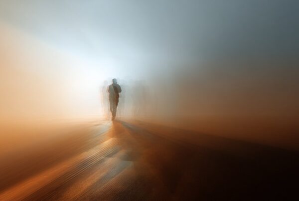 A blurred figure walking through a hazy desert landscape, symbolizing confusion and disorientation often linked to street names for inhalants.
