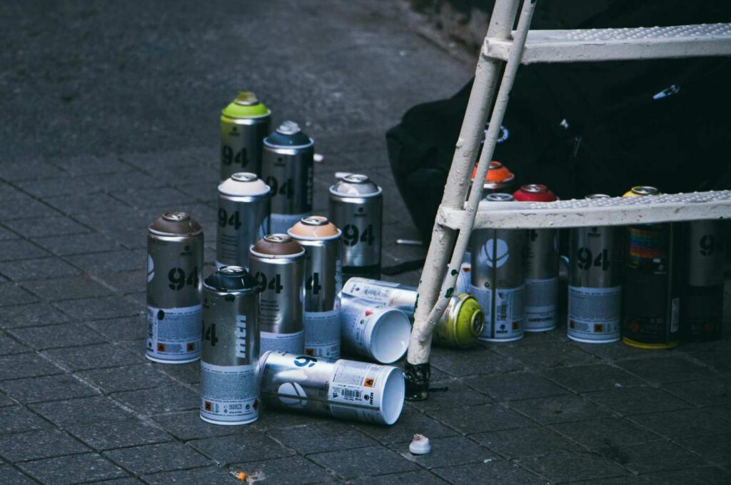 A group of scattered spray paint cans on a city sidewalk, representing common items associated with street names for inhalants.